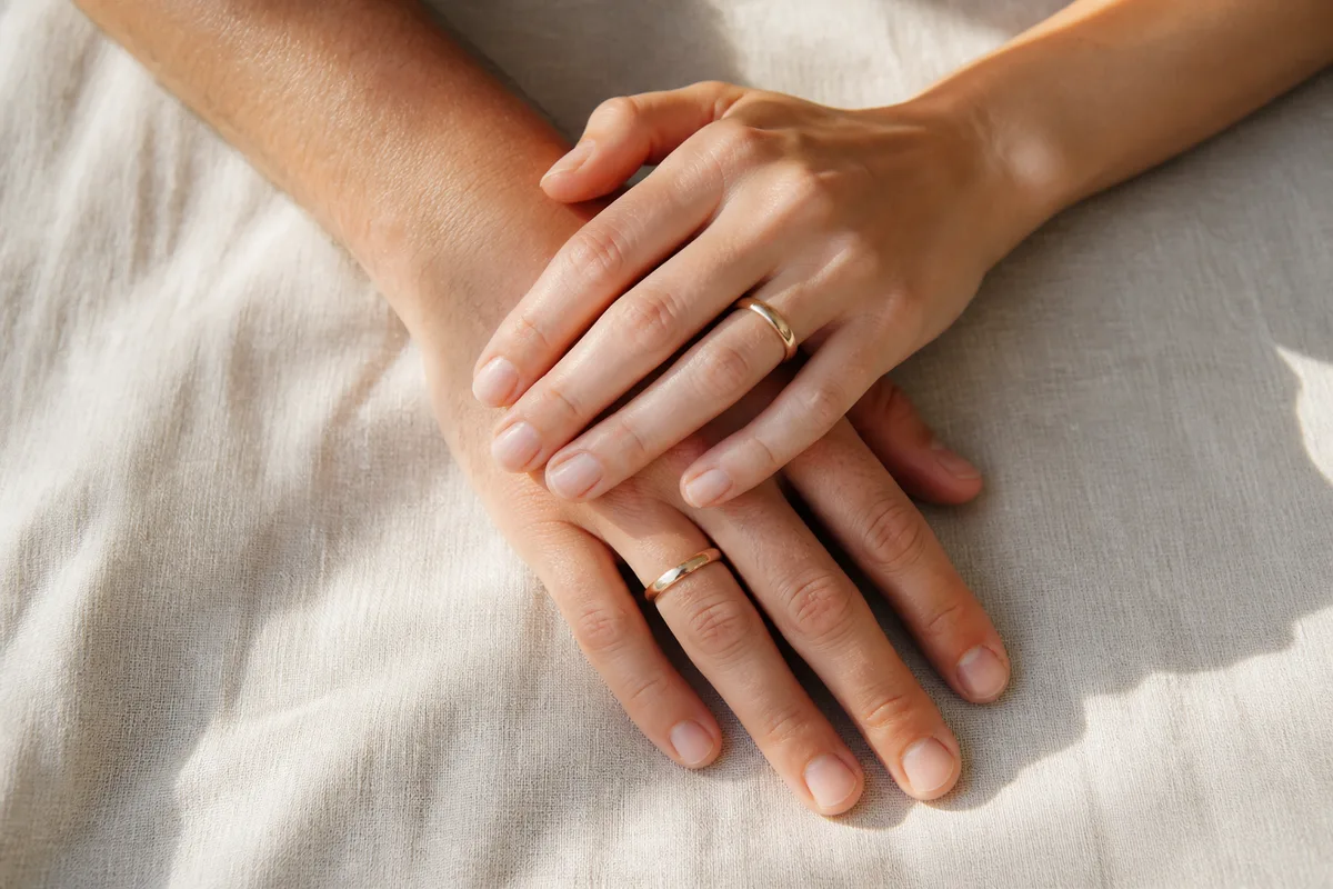 Mains d&rsquo;un couple entrelacées sur une nappe en lin clair