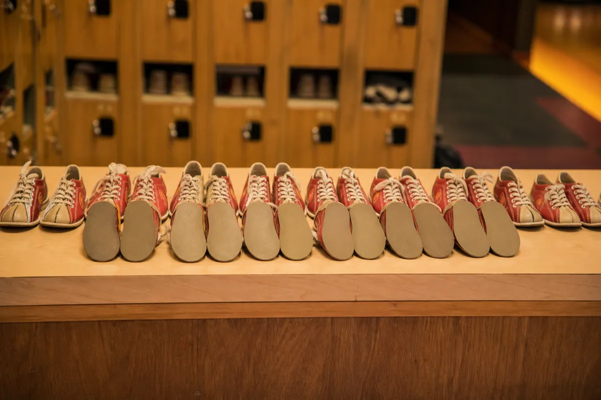 Rangée de petites chaussures de bowling bicolores alignées sur le comptoir d&rsquo;une salle